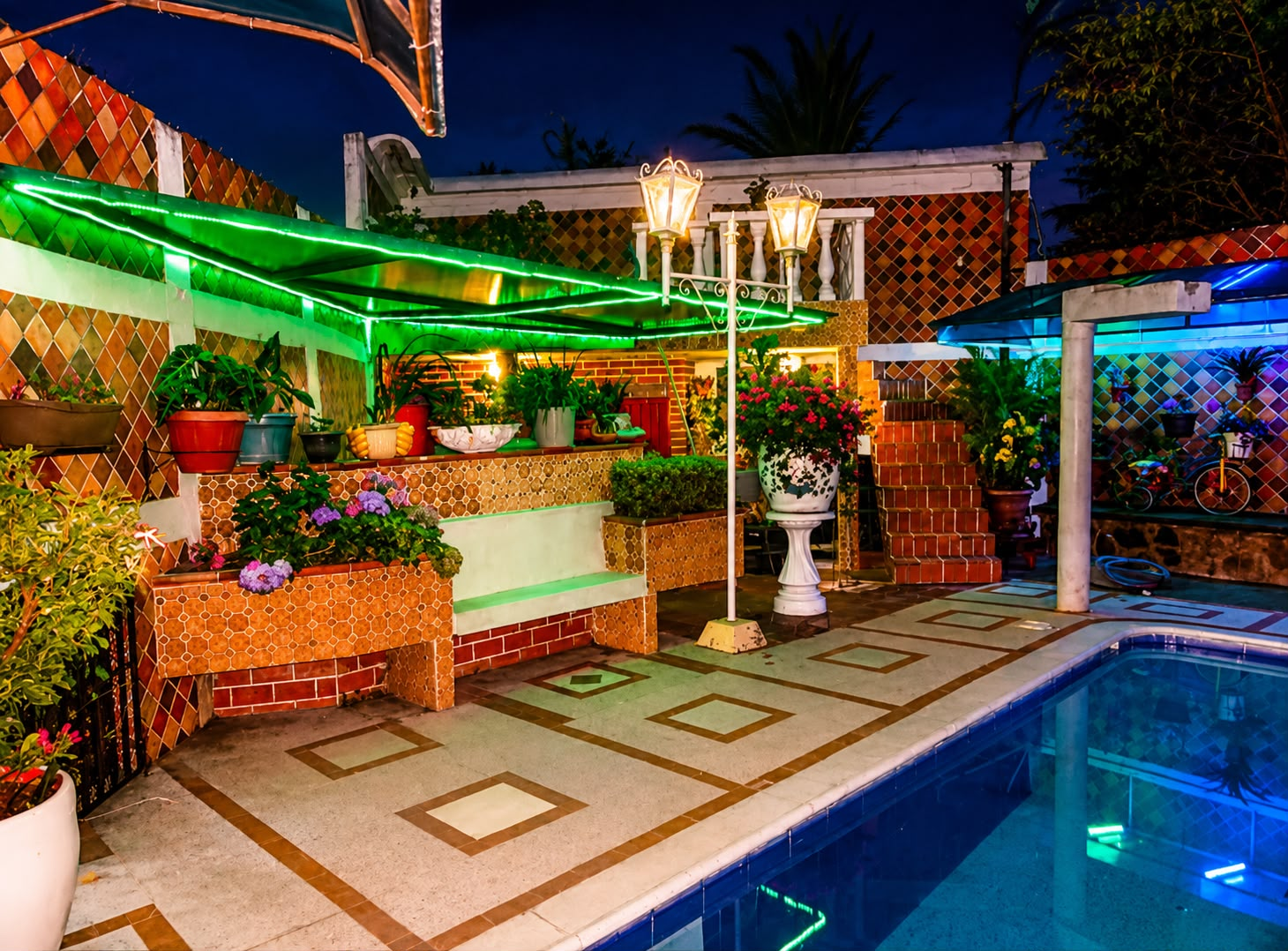 Terraza junto a la piscina iluminada de noche