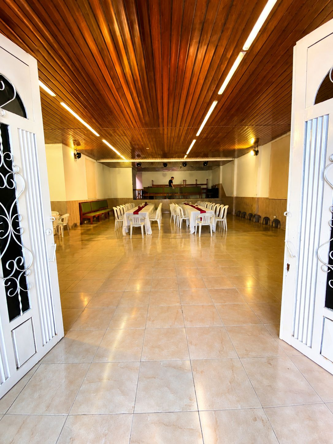 Salón de eventos con techo de madera y mesas vestidas de blanco