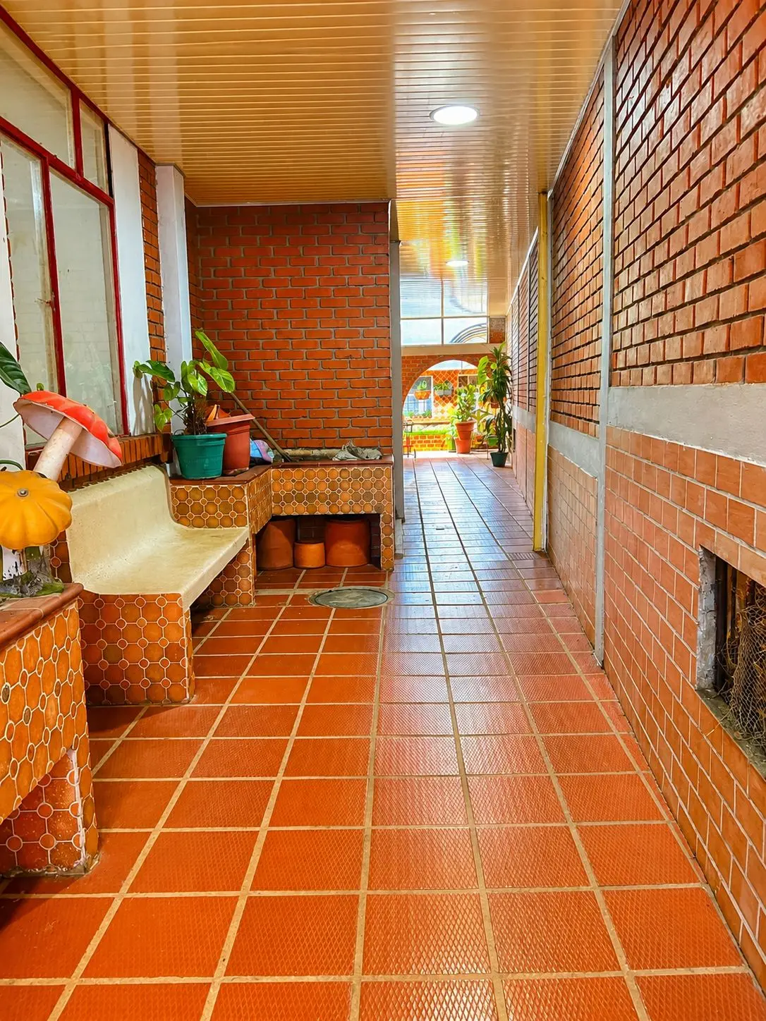 Corredor de ladrillo con banca de azulejo y plantas